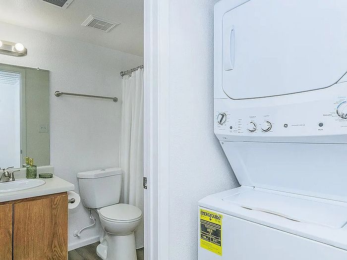 Modern apartment bathroom with in-unit washer and dryer, featuring stylish fixtures and ample utility space.