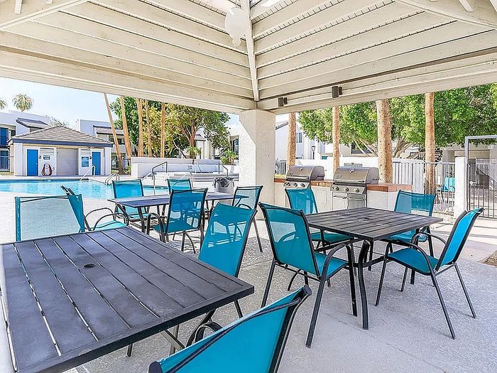 Inviting outdoor poolside area with modern seating, shade structures, and convenient barbecue grills.