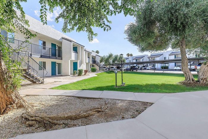 Charming apartment complex with modern two-story buildings, lush green lawns, and mature trees creating a serene environment.