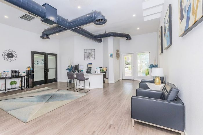 Modern apartment lobby featuring sleek black furniture, elegant reception desk, and stylish decor with contemporary artwork.