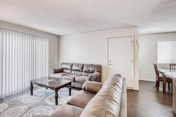 Inviting living room with plush leather sofas, elegant coffee table, and bright natural light from large windows.