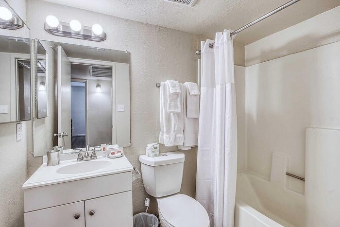 Bright, modern bathroom with stylish vanity, large mirror, and pristine shower/tub combo for a fresh start to your day.