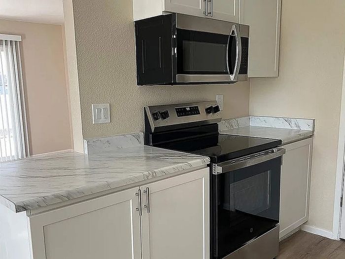 Modern kitchen with sleek stainless steel appliances, elegant marble countertops, and contemporary white cabinetry.