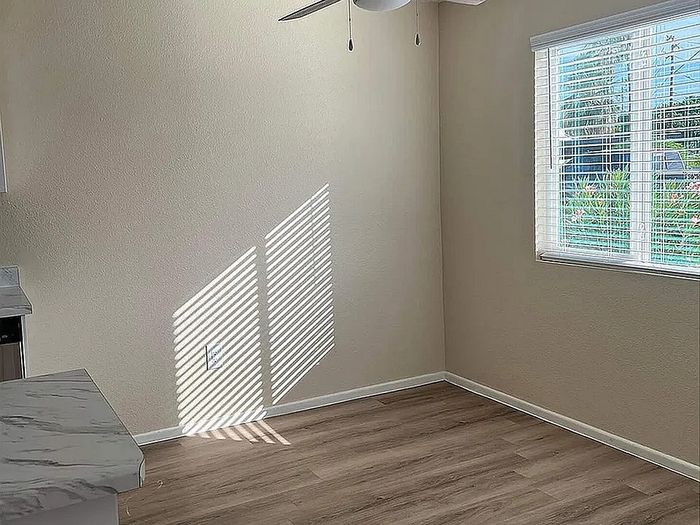 Bright and inviting room with natural light, featuring stylish wood flooring and a modern ceiling fan.