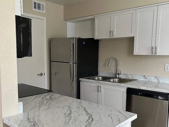 Modern kitchen with chic marble countertops, sleek stainless steel appliances, and elegant white cabinetry.