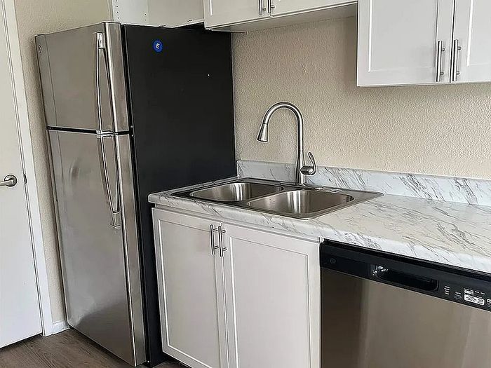 Modern kitchen with sleek stainless steel appliances, elegant marble countertops, and convenient double sink.
