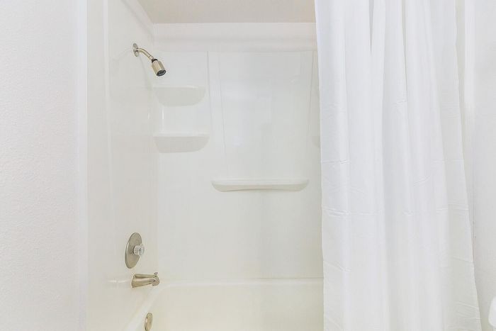 Bright, modern bathroom with sleek white bathtub and elegant shower curtain, ideal for a refreshing retreat.