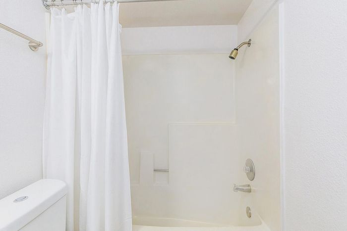 Bright and modern bathroom featuring a sleek shower with a white curtain, perfect for a refreshing start to your day.