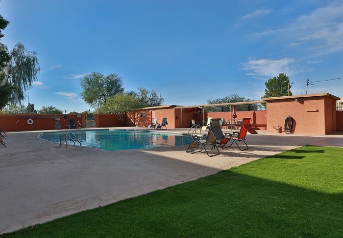 Inviting outdoor pool area featuring comfortable lounge chairs and vibrant greenery under a clear blue sky.