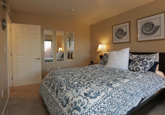 Charming bedroom with elegant decor, featuring a plush bed with patterned bedding, ambient lighting, and artistic wall accents.