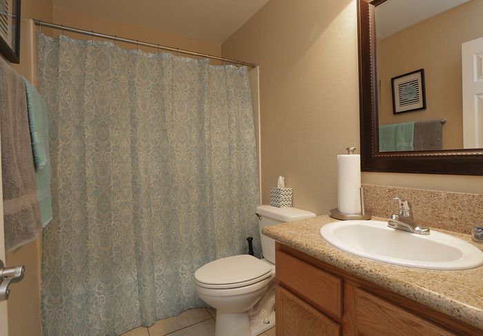 Elegant bathroom with patterned shower curtain, sleek granite countertop, and modern fixtures in a welcoming space.