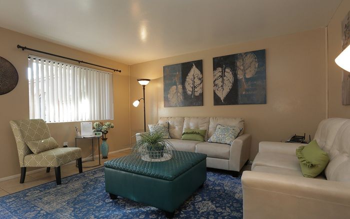 Inviting living room with elegant beige sofas, chic blue accents, and modern artwork creating a cozy atmosphere.