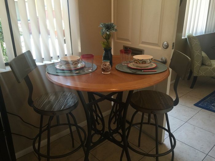 Charming dining nook with a round wooden table, stylish metal chairs, and elegant table setting, perfect for cozy meals.