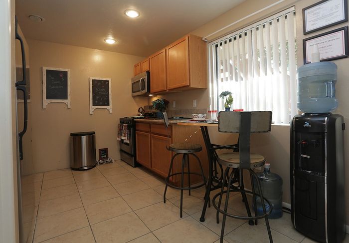 Charming kitchen with modern stainless steel appliances, cozy countertop seating, and abundant natural light through vertical blinds.
