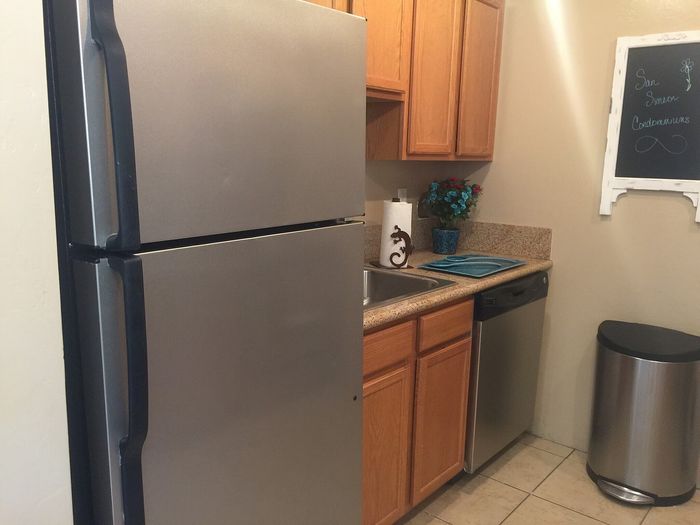 Modern kitchen with stainless steel appliances, elegant granite countertops, and warm wooden cabinetry, perfect for stylish condominium living.
