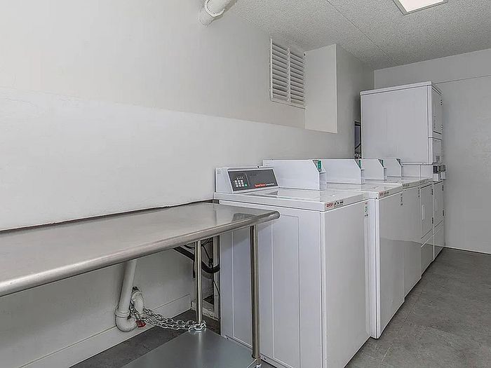 Modern apartment laundry room with multiple efficient washing machines and a sleek folding table, offering convenience and style.