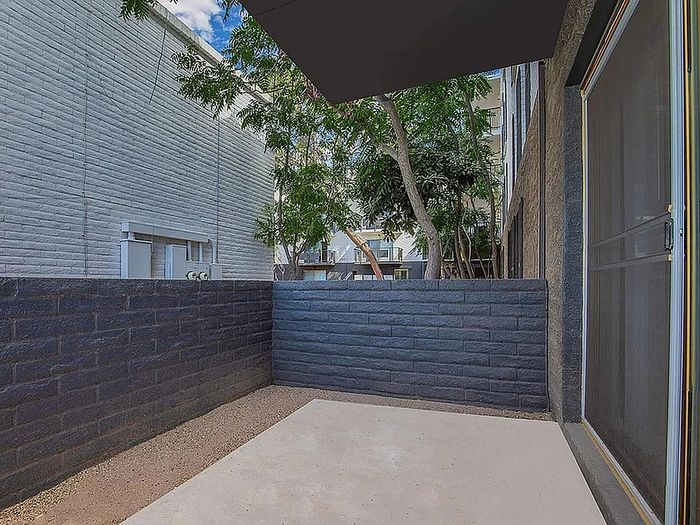 Charming patio space with modern brick walls and leafy views, perfect for outdoor relaxation.