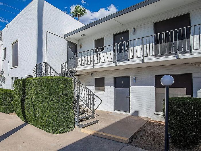 Sunny, modern apartment exterior with elegant stairs and lush greenery, perfect for comfortable urban living.