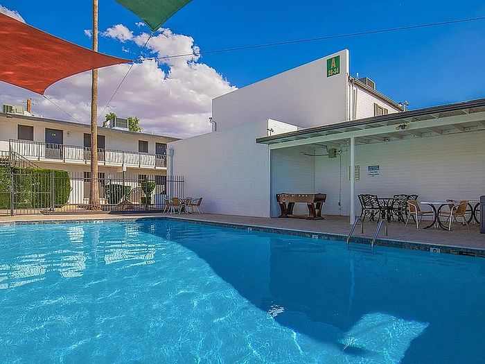 Inviting apartment community pool area with bright blue water, shaded seating, and recreational space, perfect for relaxation and social gatherings.