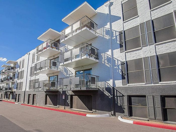Modern apartment building showcasing stylish balconies and sleek architectural design, bathed in bright sunlight.