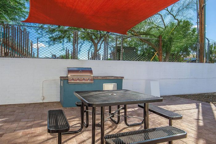 Chic outdoor patio with modern grill and shaded seating area, perfect for entertaining and enjoying sunny days.