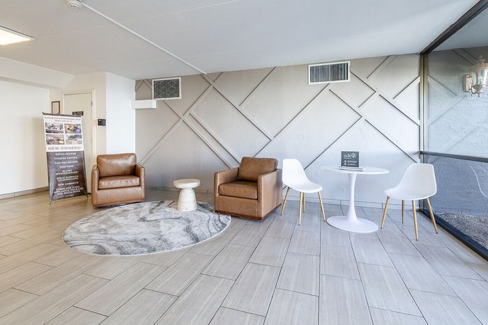Bright and modern seating area with stylish leather armchairs and chic white chairs, perfect for relaxation and socializing in a contemporary apartment setting.
