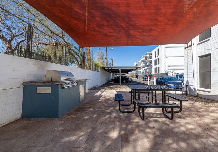 Inviting outdoor space featuring a modern grill and shaded picnic area, perfect for al fresco dining in a contemporary apartment setting.