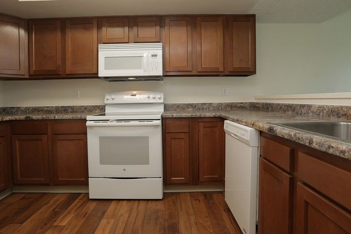 Charming kitchen with modern wood cabinetry, elegant countertops, and sleek white appliances.