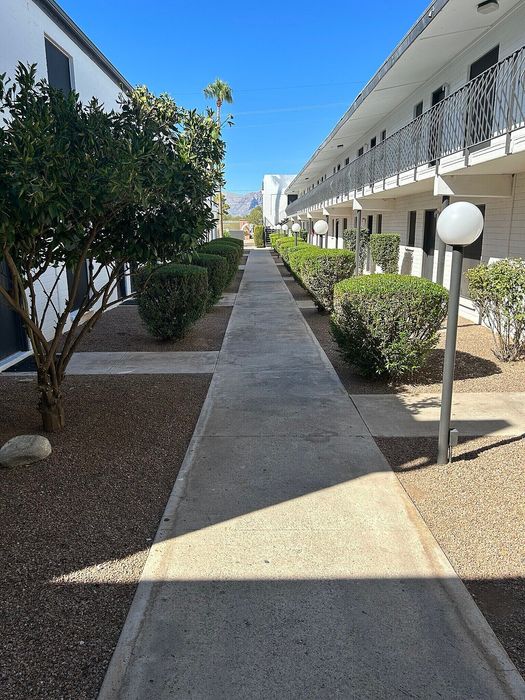 Charming apartment complex with lush landscaping, inviting walkway, and stunning mountain views.