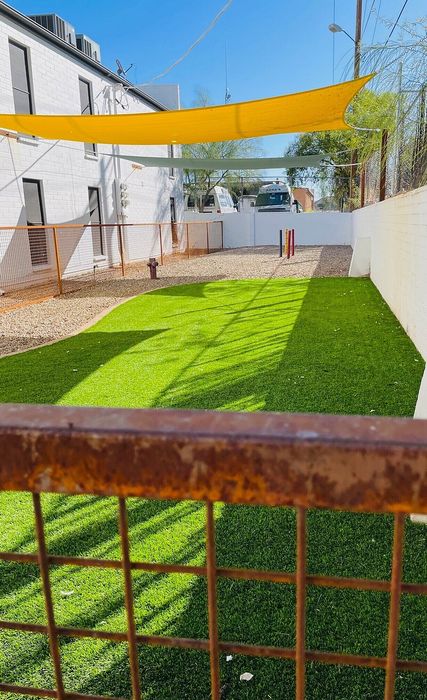 Inviting outdoor space featuring vibrant artificial grass and decorative shade sails, perfect for relaxation.