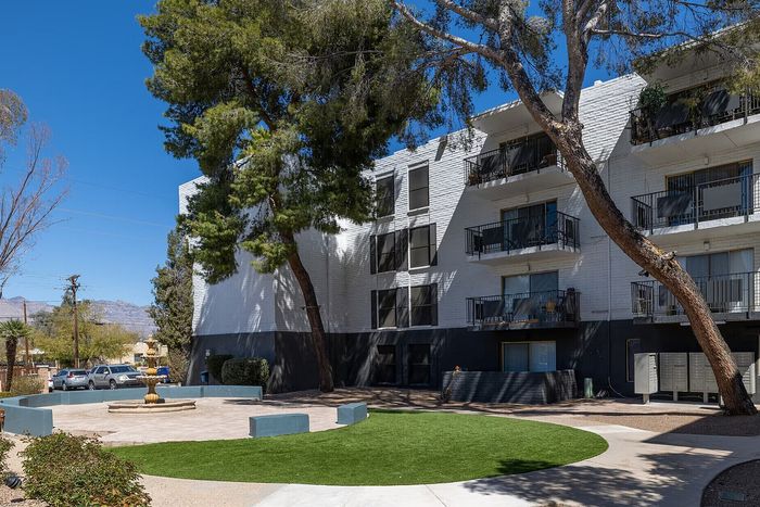 Modern apartment building with inviting balconies and lush green outdoor area under a clear blue sky.