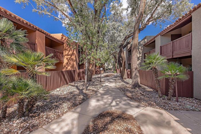 Tranquil apartment complex with lush greenery, featuring shaded walkways and private balconies.