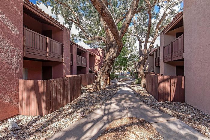 Charming apartment exterior with rustic wooden balconies and a serene tree-lined pathway providing a tranquil atmosphere.