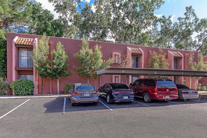 Charming apartment exterior with terracotta roofing, surrounded by lush greenery and convenient parking.
