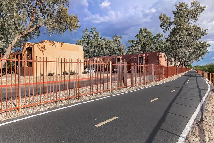 Charming apartment complex surrounded by lush trees and scenic pathway, promising serene living.