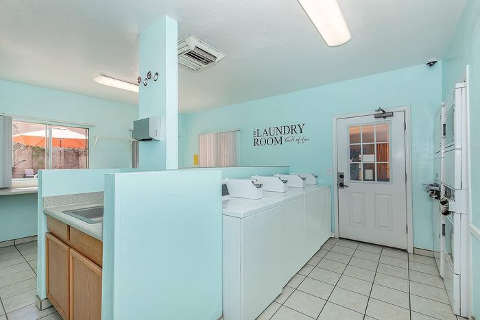 Bright and inviting laundry room with modern washers, ample folding space, and cheerful pastel blue walls.