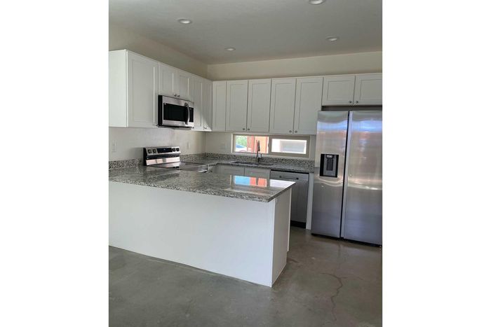 Modern kitchen with sleek stainless steel appliances, granite countertops, and stylish white cabinetry.