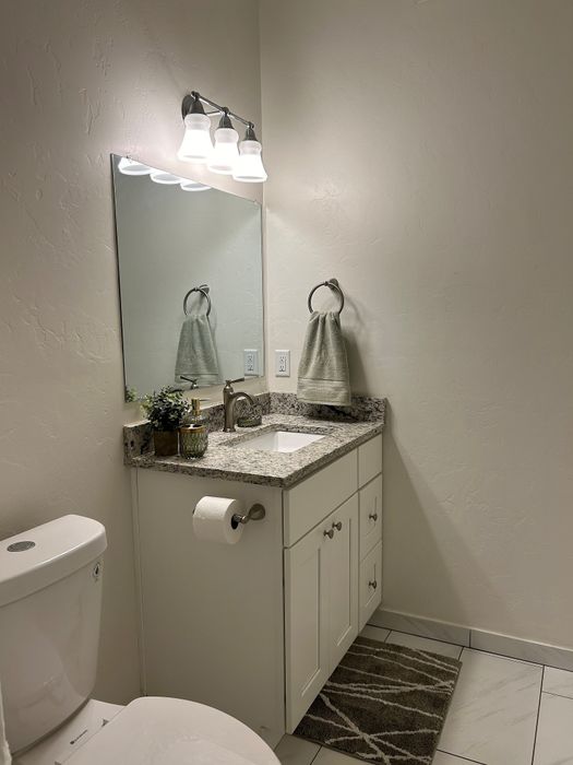 Modern bathroom with sleek granite countertop, elegant lighting, and stylish cabinetry exuding sophistication and comfort.