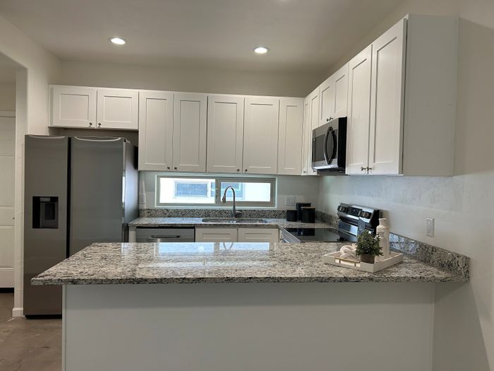 Modern kitchen with sleek stainless steel appliances, elegant granite countertops, and pristine white cabinetry.
