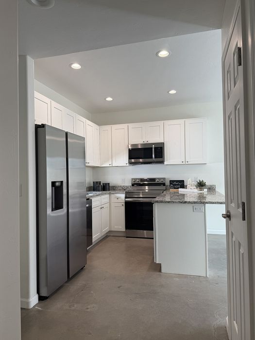 Sleek modern kitchen with stainless steel appliances, elegant white cabinetry, and granite countertops, perfect for gourmet cooking.