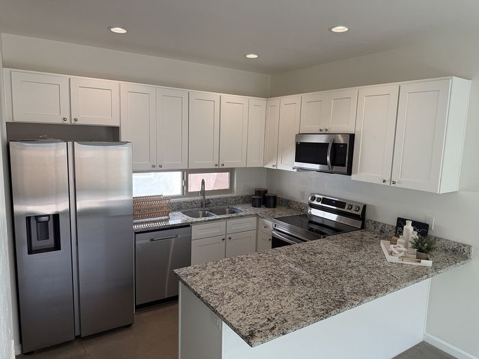 Modern kitchen with sleek granite countertops, stainless steel appliances, and ample white cabinetry.