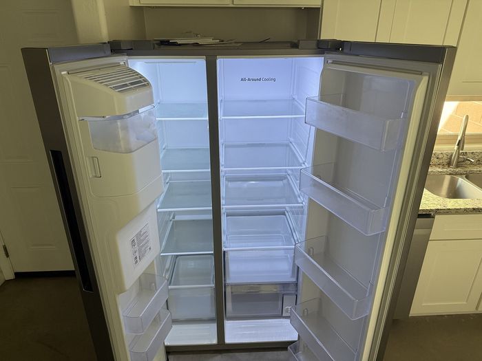 Modern stainless steel double-door refrigerator with ample shelving and spacious interior, complementing a sleek, contemporary kitchen.