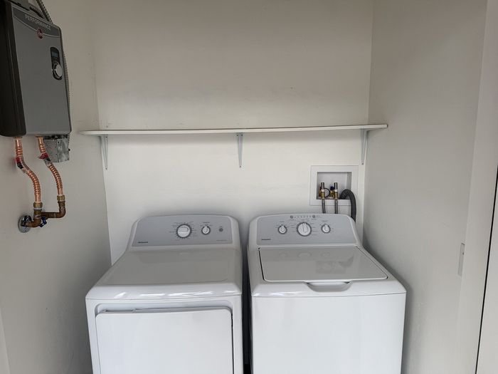 Modern laundry space featuring a sleek washer and dryer set, complemented by efficient shelving and stylish piping.