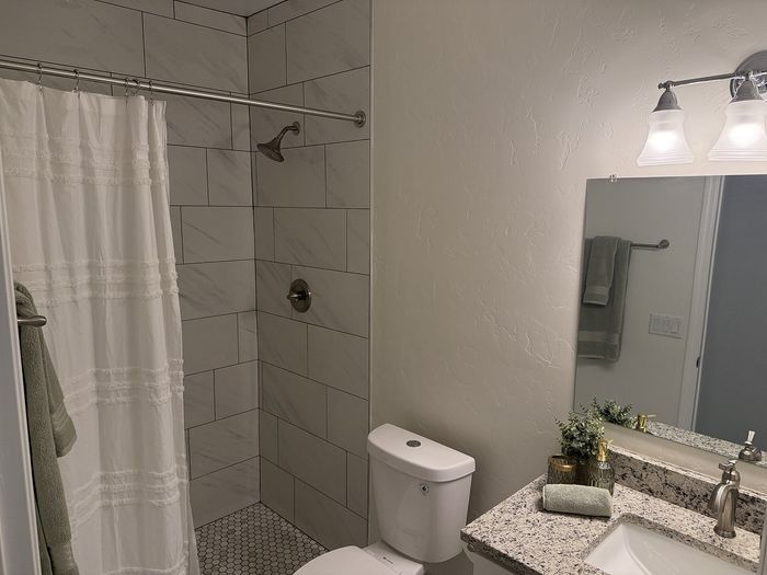 Elegant bathroom with sleek marble tile shower, modern fixtures, and a pristine granite countertop.
