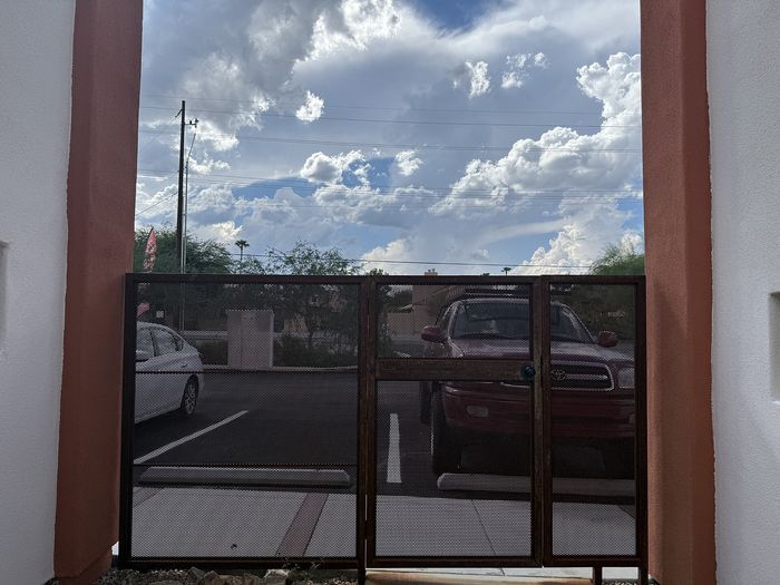 Inviting view from a modern apartment, showcasing a stylish entrance with parked vehicles and picturesque clouds enhancing the scenery.