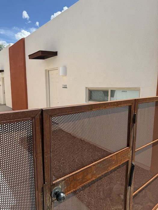 Charming exterior of an apartment with a modern rustic gate and pristine walls under a clear blue sky.