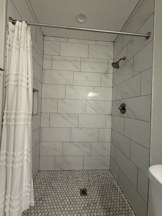 Elegant bathroom with modern white-tiled shower and stylish curtain, offering a serene and refreshing space.