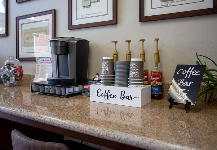 Inviting coffee bar with a modern coffee machine, assorted syrup bottles, and a charming display of coffee cups.