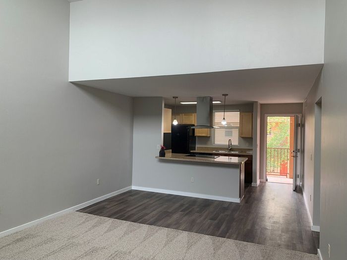 Modern apartment interior with open-concept kitchen and living area, featuring stylish wooden flooring and ample natural light.