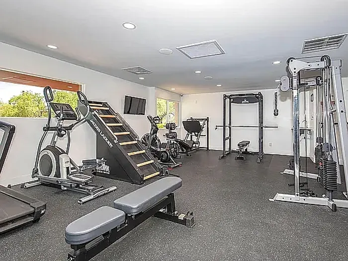 Modern fitness center featuring state-of-the-art equipment, including weight machines, cardio machines, and exercise balls, in a bright and spacious setting.